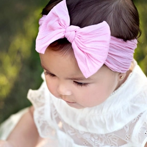 Nahaufnahme eines rosa Baby Stirnbandes mit großer Schleife aus weichem Strickstoff