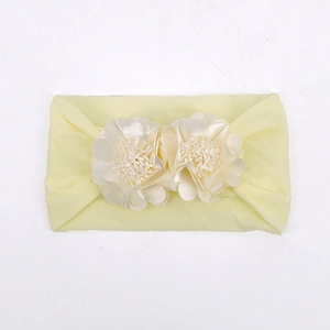 Detail of light yellow elastic baby headband featuring double fabric floral decorations