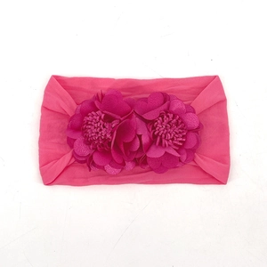 Detailed close-up of a bright pink baby headband featuring handmade fabric flower petals