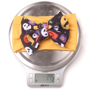 Kitchen scale displaying the 17.5g lightweight measurement of Halloween pumpkin bow headband