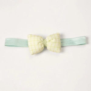 Close-up of yellow checkered bow on mint green baby headband with soft cotton texture