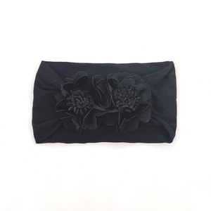 Detail of baby elastic headband featuring double floral ornaments in black soft fabric