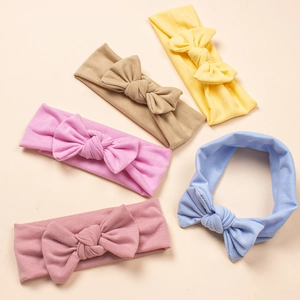 Flat lay of five soft colorful bow headbands for infants in pastel knit fabric