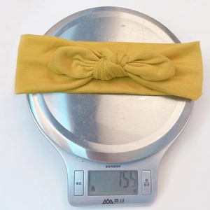 Détail d'un bandeau bébé jaune moutarde sur une balance affichant un poids de 15,5g