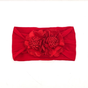 Detail view of red elastic baby headband with two 3D fabric flowers on white background