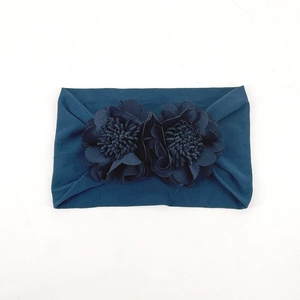 Detail shot of navy blue elastic baby headband featuring handmade floral fabric ornaments