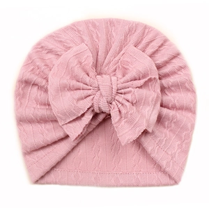 Detailed macro view of pink cable knit baby hat with a large bow decoration