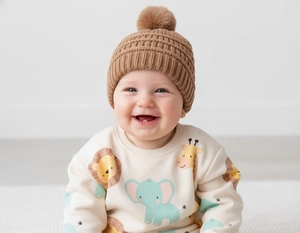 Detail of baby winter knit hat featuring a soft fur pompom and ribbed knit texture