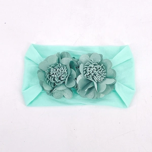 Detail view of mint green elastic baby headband featuring delicate handmade fabric flowers