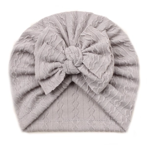 Detail of grey baby turban hat with oversized bow and textured cable knit fabric