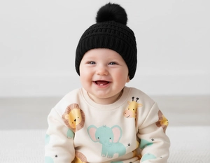 Detail of black knit baby beanie featuring a thick ribbed texture and fluffy pom-pom top