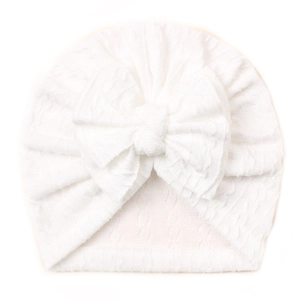 Detailed view of white knitted baby turban hat with a large decorative bow