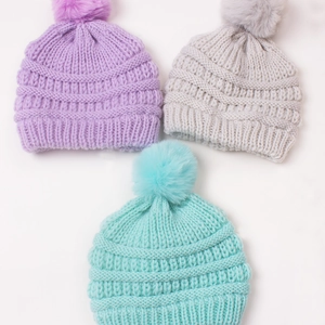 Three warm knit baby hats with large pom poms in violet, grey, and mint green colors