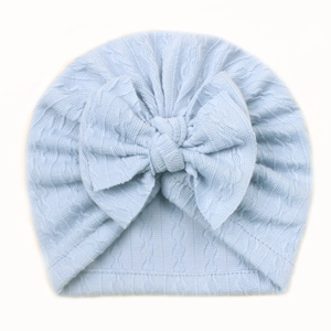Detail of light blue baby beanie featuring soft cable knit texture and a large bow accent