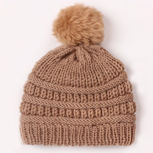 Close-up of brown knit baby beanie showing thick vertical texture and a large soft pom pom