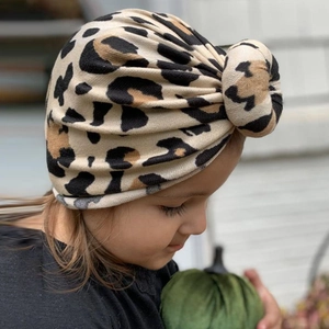 Detail of baby leopard print turban hat with top bun knot on soft cotton fabric