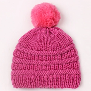 Close-up of rose pink knit baby hat featuring thick vertical texture and large fluffy pompom