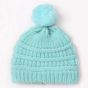 Close-up of light blue knit baby hat with soft faux fur pom-pom and thick ribbed texture