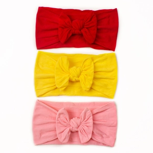 Detailansicht von drei Baby-Stirnbändern aus Nylon mit großen Schleifen in Rot, Gelb und Rosa