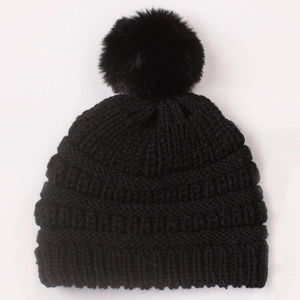 Detail of black knit baby beanie showing cable textures and a fluffy faux fur pom-pom