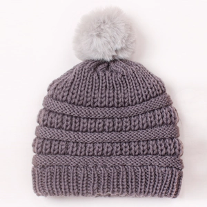 Close-up of mauve knit baby hat featuring chunky texture and a large grey faux fur pompom