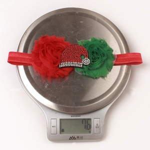Detail van kerst hoofdband voor baby met rode bloem en kerstmuts op een weegschaal
