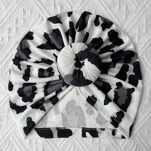 Close-up of baby donut turban hat with black and white leopard print in soft knit fabric
