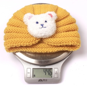 Winter knit baby bear hat in ginger yellow weighing 44.6g on a digital scale