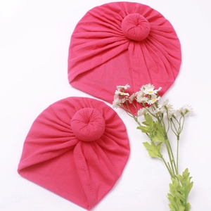 Détail de deux bonnets en tricot rose fuchsia avec nœud donut pour maman et bébé