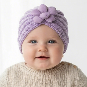 Detail einer lila Strickmütze für Babys mit großer 3D-Blume für den Winterkomfort