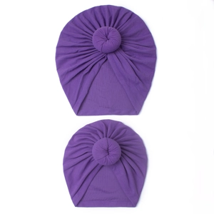 Détail de deux turbans violets pour bébé avec nœuds donuts et tissu tricoté plissé