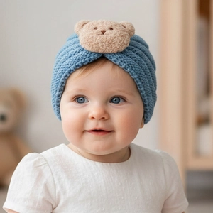 Close-up of baby knit beanie featuring a cute plush brown bear patch on light blue ribbing
