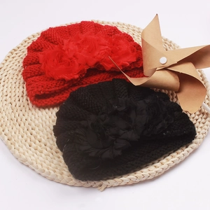 Detailed knit texture of baby winter hats in red and black with large mesh flower accents