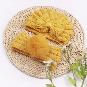 Ginger yellow knitted baby hat and headband set with decorative bow and pom-pom accents
