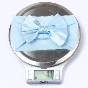 Gros plan montrant le poids de 10,8g du bandeau bébé bleu clair avec nœud en nylon