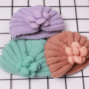 Drei gestrickte Baby-Turban-Mützen mit 3D-Blumen in weichen Pastellfarben in der Detailansicht