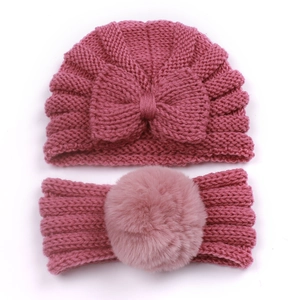 Detail of baby knitted bow hat and faux fur pompom headband in dusty pink color
