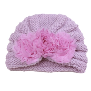 Detail of purple knitted baby hat featuring three 3D pink fabric flowers and lace mesh