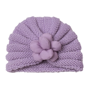 Nahaufnahme einer lila Strickmütze für Babys mit 3D-Stoffblume und gerippter Struktur