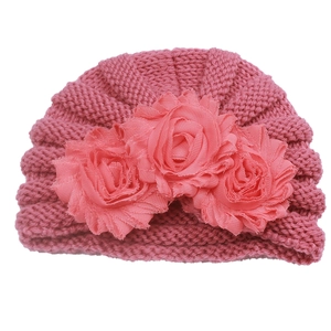 Close-up of knit baby turban hat featuring three large decorative fabric rose flowers