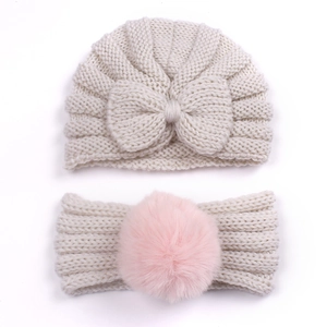 Detail of baby knit hat with beige bow and matching headband with soft pink pompom