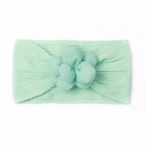 Détail du bandeau bébé vert menthe avec texture en maille douce et grande fleur décorative