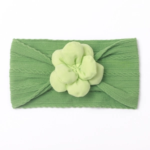 Détail d'un bandeau bébé en nylon avec texture côtelée et fleur en tissu vert herbe