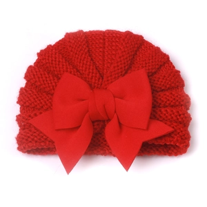 Gros plan sur le bonnet en tricot rouge pour bébé avec maille texturée et grand nœud