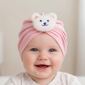 Pink soft cotton baby hat with a cute white plush bear patch and pleated fabric detail