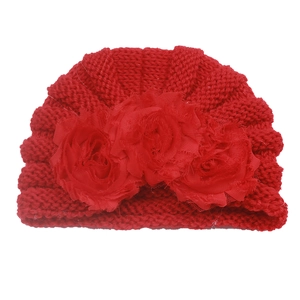 Detail of red knit baby turban hat featuring three large 3D fabric rose decorations