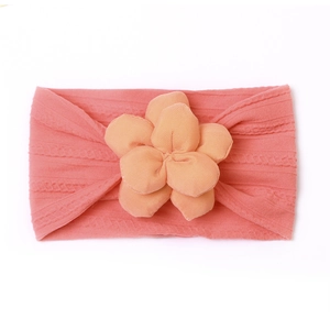Gros plan sur un bandeau bébé rose corail en nylon souple avec fleur en relief 3D