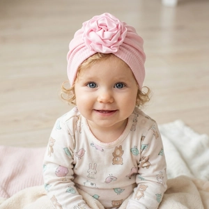 Close-up of baby girl pink ribbed knit beanie with a decorative large satin rose flower