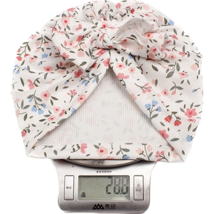 Weight display of baby floral turban hat showing 28.8g on scale with large ribbed bow