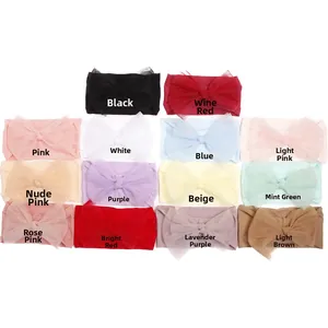 Flat lay of 14 colorful nylon tulle bow headbands for baby girls on a white background
